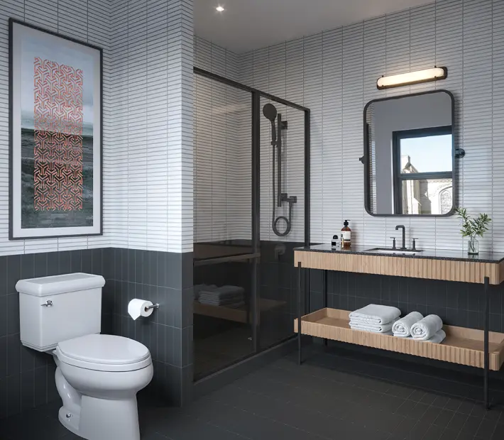 Postmark Hotel guest suite bathroom with bright lighting, folded towels, and glass shower