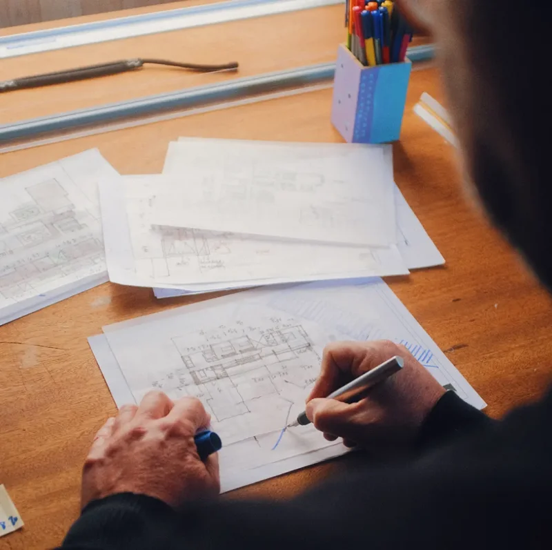 Over shoulder photo of architect at desk sketching blueprints