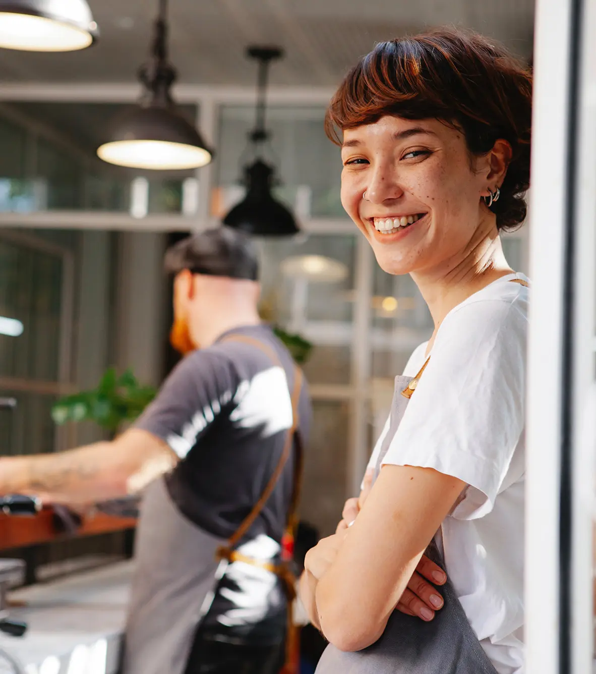 Restaurant staff in kitchen with female staff member smiling at camera